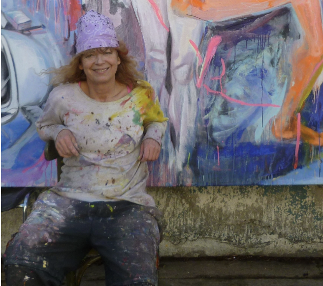Ella Helman in her studio posing in front of her painting Trois Muses